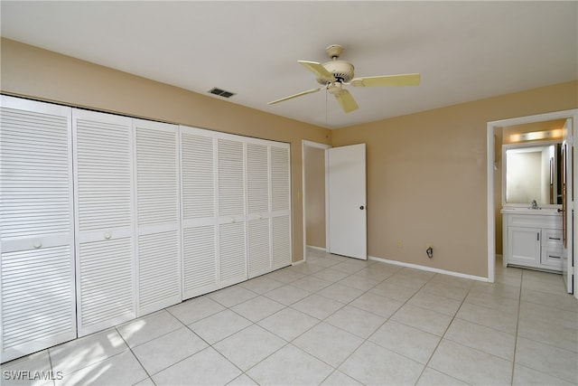 unfurnished bedroom featuring ceiling fan, a closet, connected bathroom, and light tile patterned floors