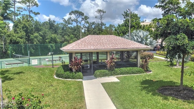 surrounding community featuring tennis court and a lawn