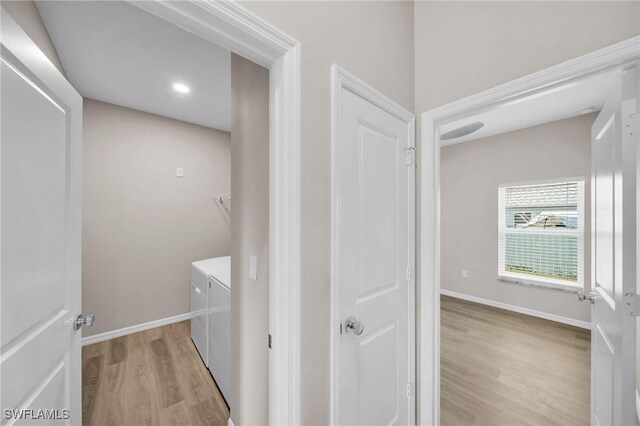 clothes washing area with washing machine and dryer and light wood-type flooring