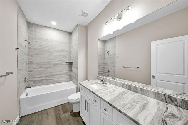 full bathroom with toilet, vanity, hardwood / wood-style flooring, and tiled shower / bath