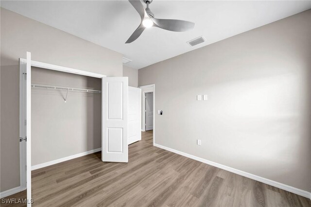 unfurnished bedroom featuring ceiling fan, wood-type flooring, and a closet