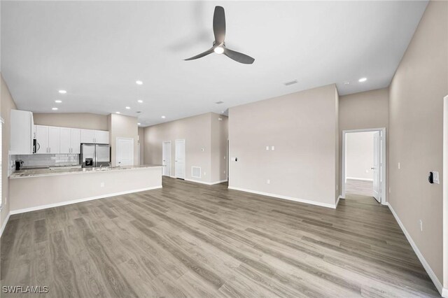 unfurnished living room with ceiling fan, high vaulted ceiling, and light wood-type flooring