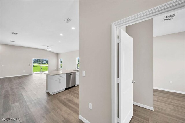 kitchen with white cabinets, dishwasher, wood-type flooring, and light stone counters