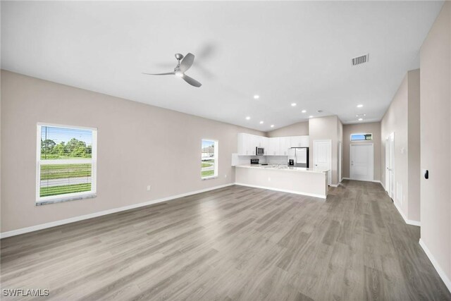 unfurnished living room with ceiling fan, vaulted ceiling, and light hardwood / wood-style floors