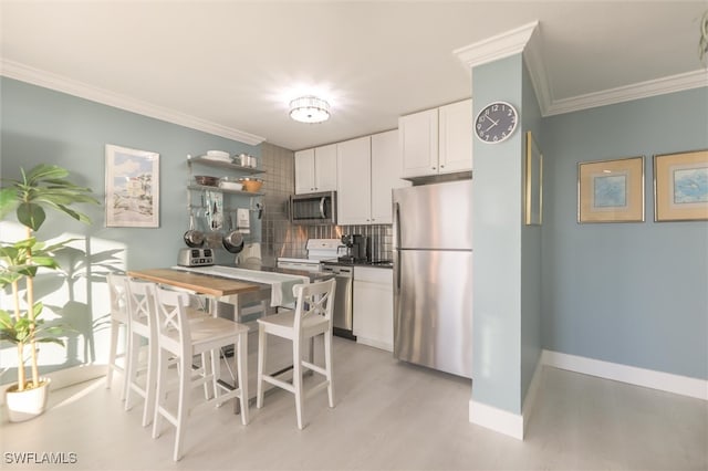 kitchen featuring ornamental molding, tasteful backsplash, stainless steel appliances, white cabinets, and light hardwood / wood-style floors