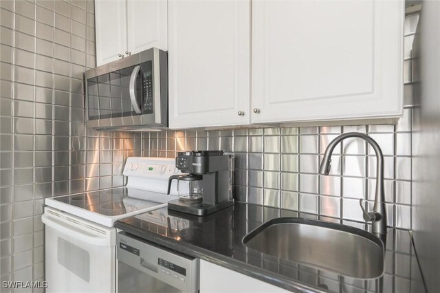 kitchen with white cabinetry, backsplash, stainless steel appliances, and sink