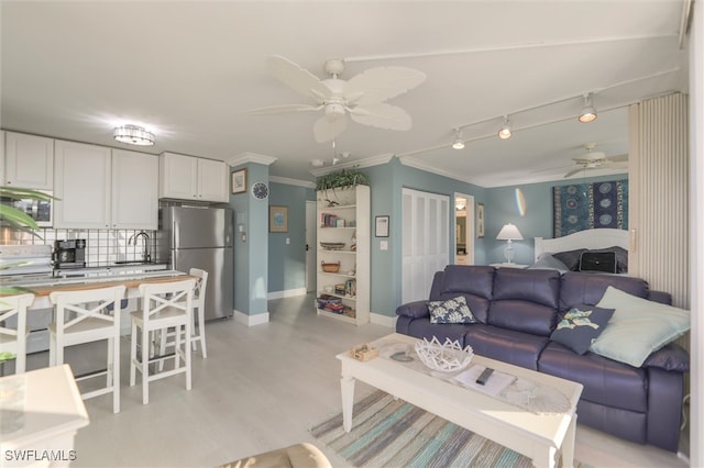 living room with light wood-type flooring, ceiling fan, crown molding, and sink