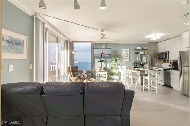 living room featuring ceiling fan, expansive windows, and crown molding