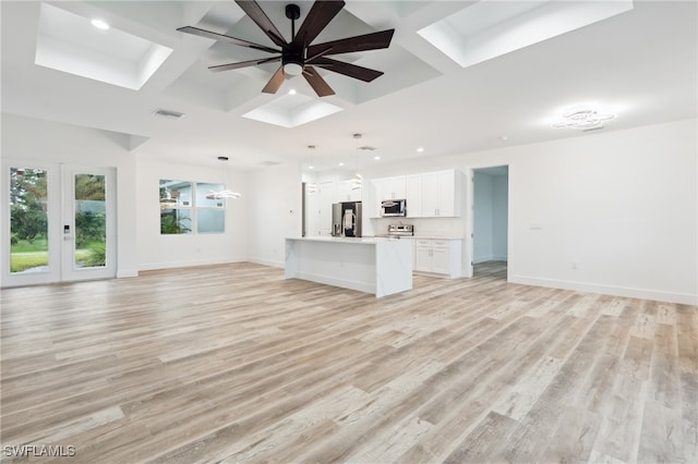 unfurnished living room with light wood-type flooring, coffered ceiling, a skylight, and ceiling fan