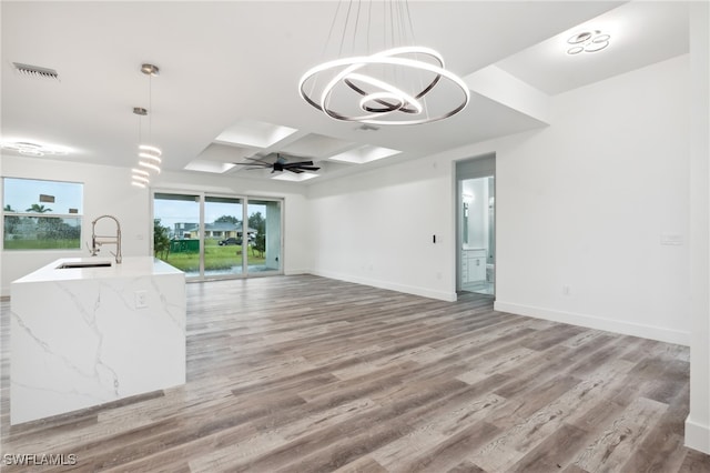 empty room featuring light hardwood / wood-style floors, ceiling fan with notable chandelier, sink, and coffered ceiling