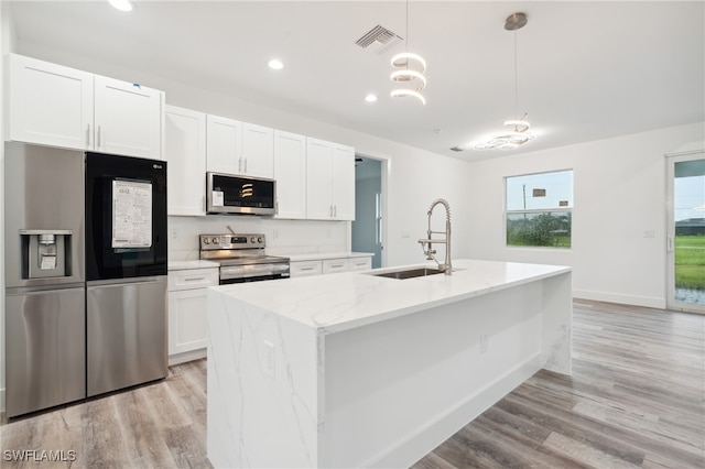 kitchen featuring light hardwood / wood-style floors, sink, stainless steel appliances, and an island with sink