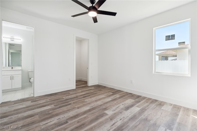 unfurnished bedroom with light wood-type flooring, sink, connected bathroom, and ceiling fan