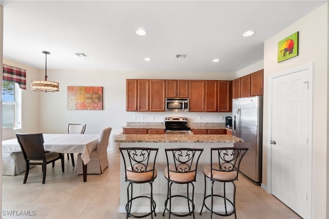 kitchen with light tile patterned flooring, a kitchen breakfast bar, a kitchen island, stainless steel appliances, and pendant lighting