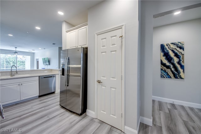 kitchen with ceiling fan, light wood-type flooring, white cabinets, sink, and stainless steel appliances