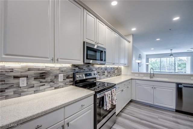 kitchen featuring ceiling fan, light hardwood / wood-style flooring, backsplash, white cabinetry, and appliances with stainless steel finishes