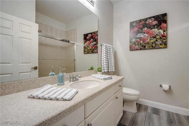 bathroom featuring wood-type flooring, toilet, vanity, and walk in shower