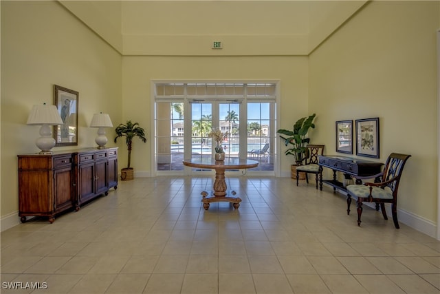 sitting room featuring light tile patterned floors, a towering ceiling, and french doors