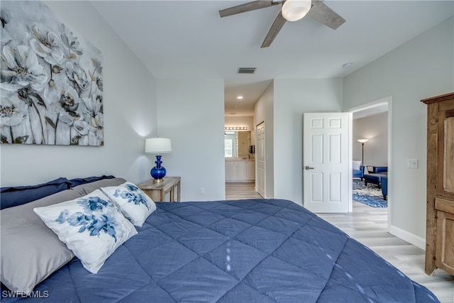 bedroom with light wood-type flooring, ceiling fan, and ensuite bath