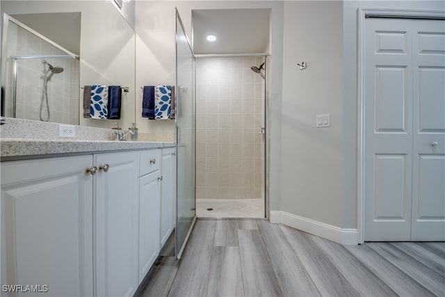 bathroom featuring tiled shower, hardwood / wood-style floors, and vanity