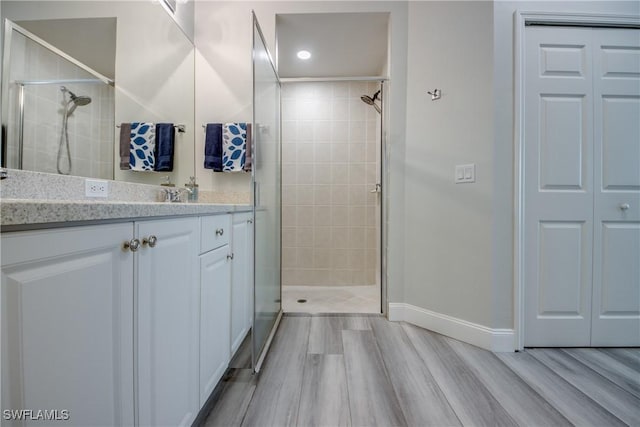 bathroom with hardwood / wood-style flooring, vanity, and a tile shower