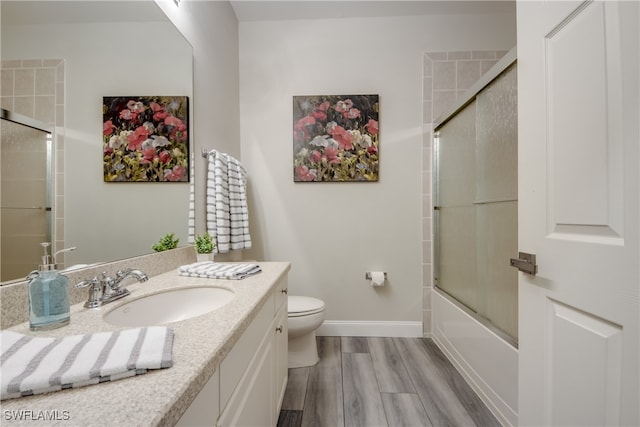 full bathroom featuring hardwood / wood-style floors, toilet, vanity, and shower / bath combination with glass door