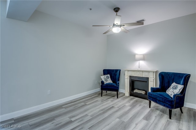 living area with ceiling fan, light wood-type flooring, and a premium fireplace