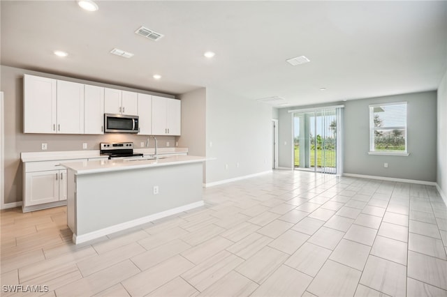 kitchen with white cabinets, a kitchen island with sink, stainless steel appliances, and sink