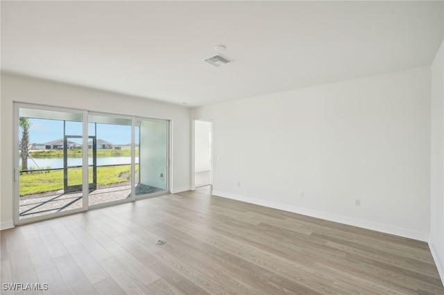 unfurnished room featuring wood-type flooring and a water view