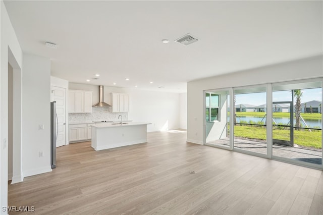 unfurnished living room featuring sink, light hardwood / wood-style floors, and a water view