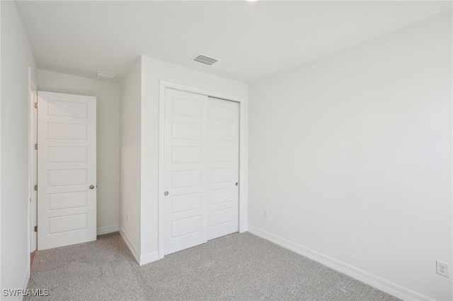 unfurnished bedroom featuring light carpet and a closet