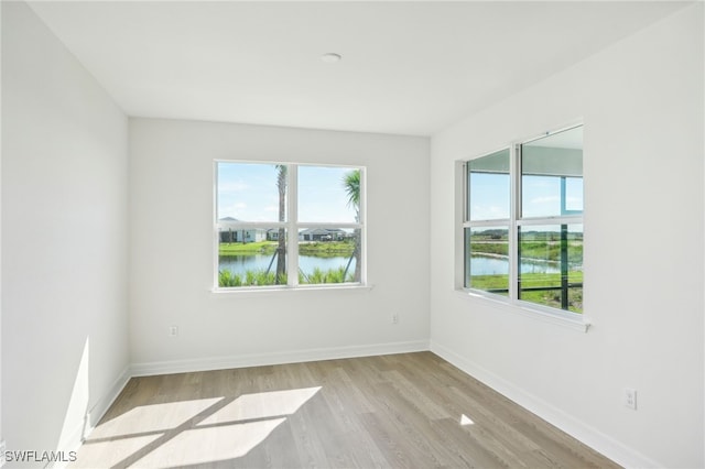 empty room featuring a wealth of natural light, a water view, and light hardwood / wood-style floors