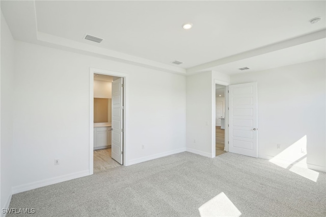 unfurnished bedroom with light colored carpet and connected bathroom