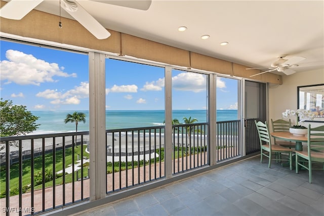 sunroom featuring a beach view, a water view, and ceiling fan