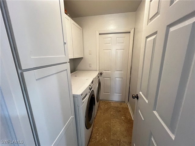 clothes washing area with dark tile patterned flooring, independent washer and dryer, and cabinets