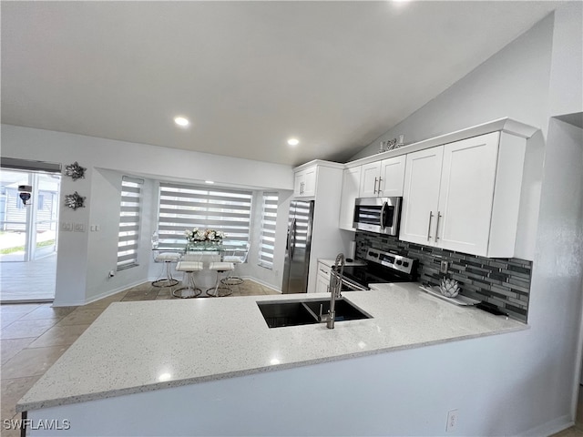 kitchen featuring backsplash, light tile patterned floors, appliances with stainless steel finishes, light stone counters, and white cabinetry