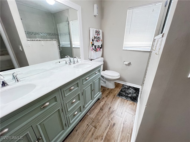 bathroom with toilet, dual vanity, and wood-type flooring