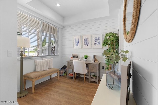 home office with light hardwood / wood-style floors and a tray ceiling