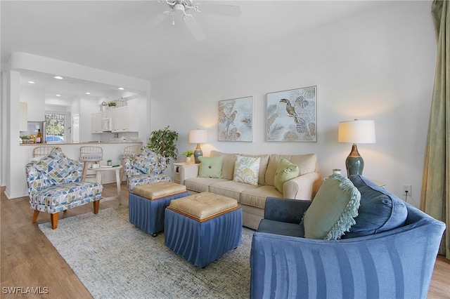 living room with light hardwood / wood-style flooring and ceiling fan