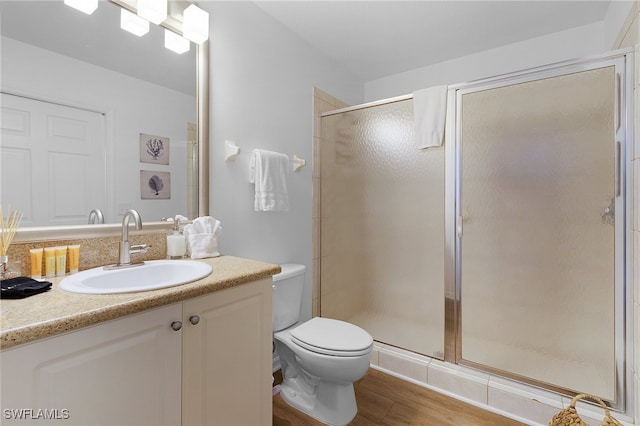 bathroom featuring an enclosed shower, toilet, vanity, and wood-type flooring