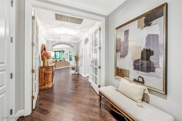 corridor featuring ornamental molding, dark wood-type flooring, and an inviting chandelier