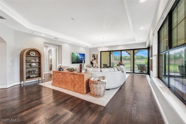 living room with a raised ceiling, built in shelves, dark hardwood / wood-style flooring, and a chandelier