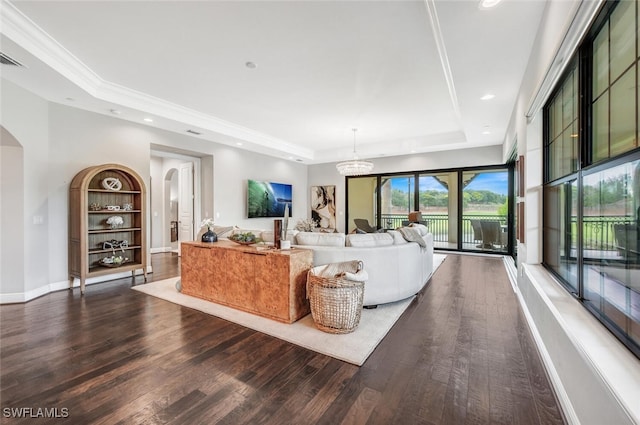 living area featuring baseboards, a raised ceiling, arched walkways, recessed lighting, and wood finished floors