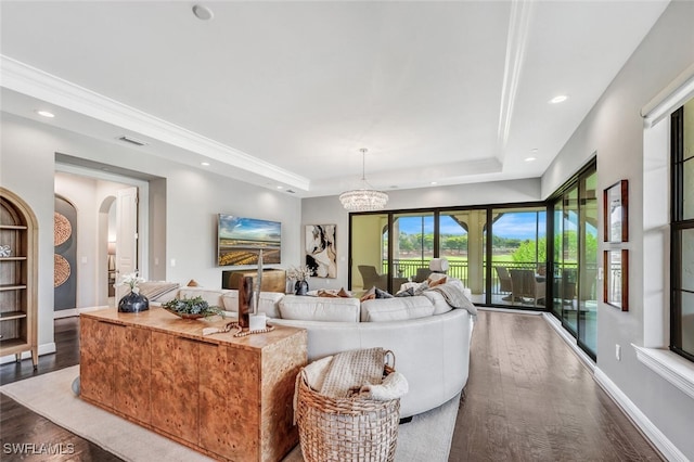 living room with dark hardwood / wood-style floors, a raised ceiling, and an inviting chandelier