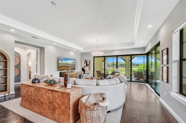 living room featuring a tray ceiling, wood finished floors, arched walkways, and visible vents