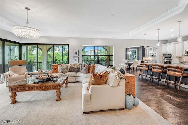 living room featuring a tray ceiling, hardwood / wood-style floors, a chandelier, and ornamental molding