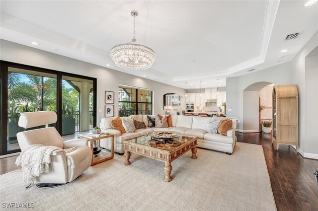 living room featuring hardwood / wood-style floors, a raised ceiling, and a notable chandelier