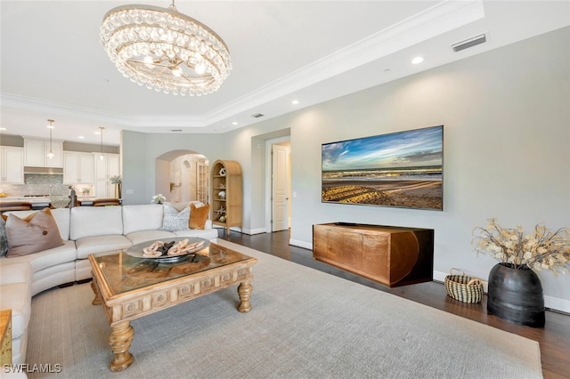 living area featuring an inviting chandelier, arched walkways, ornamental molding, visible vents, and a raised ceiling