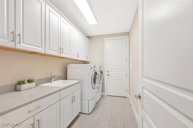 laundry area with washing machine and dryer, a sink, cabinet space, and baseboards