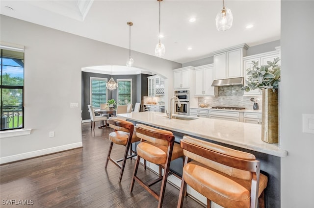 kitchen featuring appliances with stainless steel finishes, backsplash, white cabinetry, and hanging light fixtures