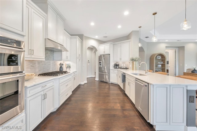 kitchen with backsplash, stainless steel appliances, white cabinetry, and hanging light fixtures